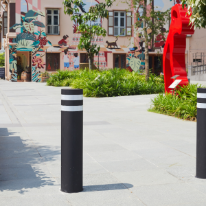 Two black bollards, each with two white reflective strips at the top of the bollard.