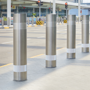 Row of stainless steel bollards with a strip of white reflective tape on the top and the bottom of each bollard.